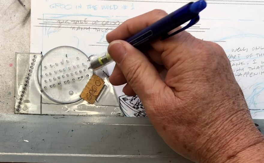 Stan Sakai using an Ames Lettering Guide to rule the lines in a panel before inking the letters. Undated photo.