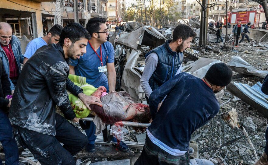 Rescue officials and others carry an injured man from the explosion site after a car bomb detonated in the southeastern Turkish city of Diyarbakir. At least eight people were killed and 100 injured in a blast outside a police building Friday morning.
