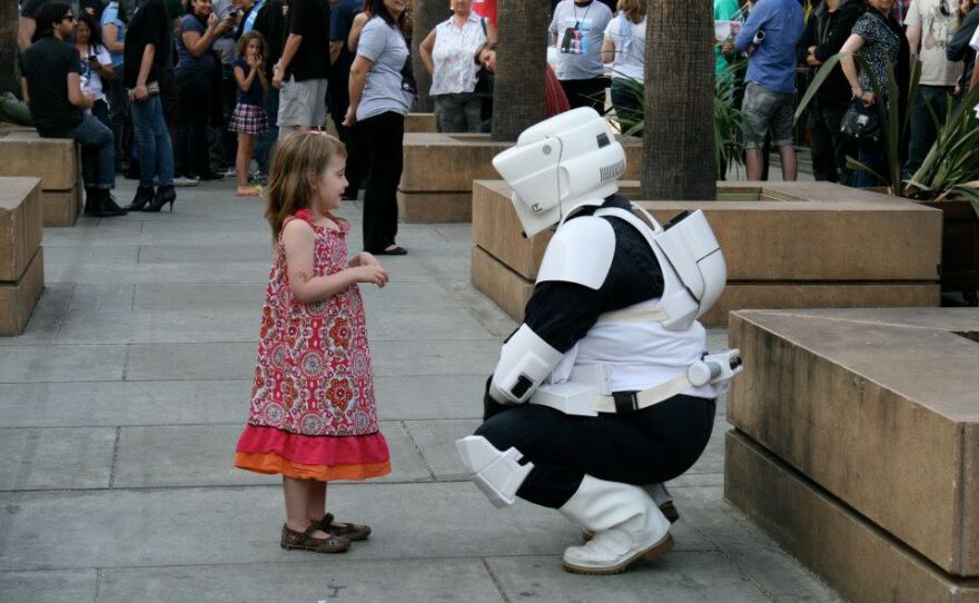 A stormtrooper reenactor greets a young girl during an appearance.