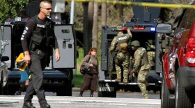Police and SWAT team members gather at the scene as employees evacuate their offices after a shooting at the Legions Place office building in Orlando, Fla., on Friday.