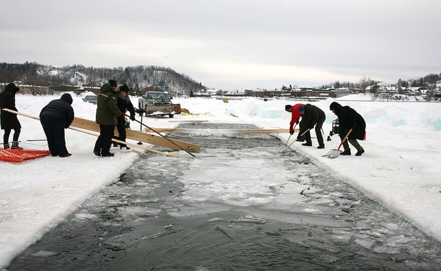 Volunteers clear ice from the swimming lanes before the start of the first Winter Swimming Championships in North America on Saturday in Newport, Vt., in Lake Memphremagog.