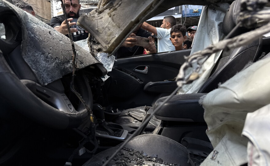 A child looks into a burned car that was targeted in an Israeli airstrike on a busy street in Gaza City on June 22, 2026. A teenage girl who was going to find internet access to take her final exams was killed in the strike.