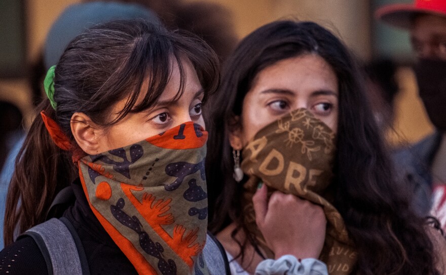Two women listen to speakers at the end of a rally and march against hate in response to the stabbing of a black girl in an apparent hate crime in the East San Diego County community of Lakeside, April 23, 2022.