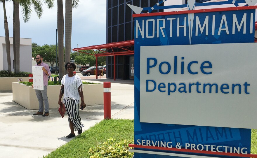 Gabriel Pendas (left) protests outside the North Miami Police Department on Thursday. The department held a news conference about the police shooting of a black behavioral therapist helping a man with autism.