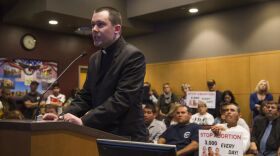 The Rev. Edward Horning addresses the El Centro City Council on Tuesday night as abortion opponents hold signs behind him, March 3, 2015.