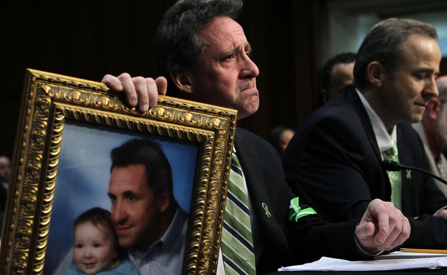 Neil Heslin, father of 6-year-old Sandy Hook Elementary School shooting victim Jesse Lewis, holds a picture of the two of them as he testifies during a hearing before the Senate Judiciary Committee in February.