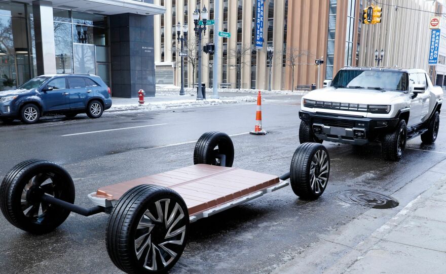 A battery pack and a GMC Hummer EV stand outside an event in Lansing, Mich., in 2022. Thea Riofrancos says car shoppers concerned about the environmental impacts of mining for batteries can choose a smaller EV, instead of a behemoth like a Hummer, to minimize the harms.