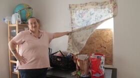 Sherry Godat reveals a plywood board in her window frame Nov. 20, 2014. Bankim Shah promised to replace the missing window before she moved in. A friend installed the plywood after months passed with no repairs.