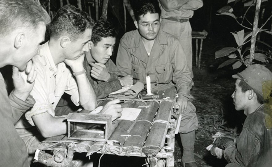 SIMINI, New Guinea, Jan. 2, 1943: Major Hawkins, Phil Ishio and Arthur Ushiro of the 32nd Infantry Division question a prisoner taken in the Buna campaign. Information from POW interrogations produced vital tactical information countless times. (National Archives photo)