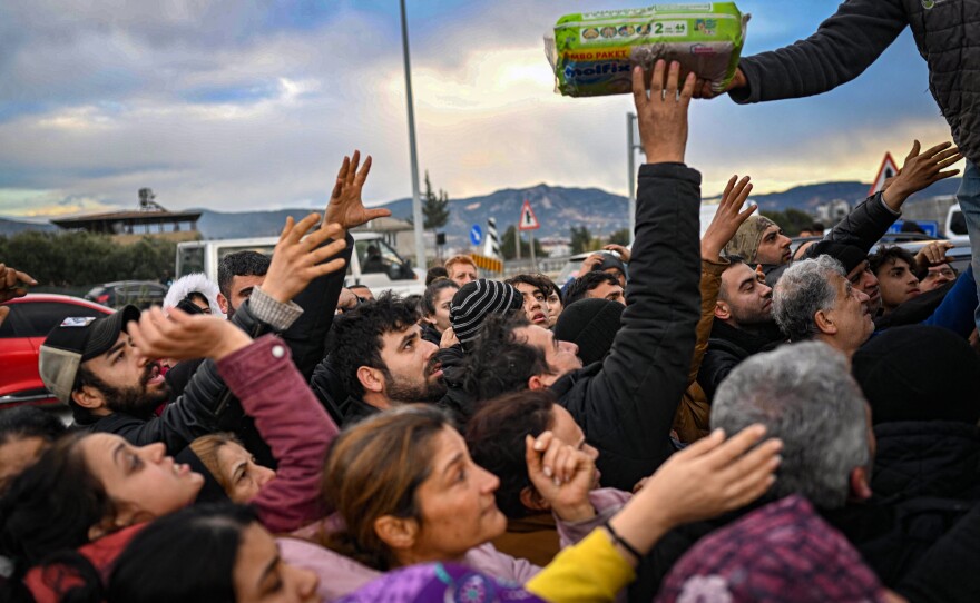 Earthquake survivors gather at a diaper distribution in Hatay, Turkey, on Feb. 7, a day after a 7.8-magnitude earthquake struck the country's southeast.
