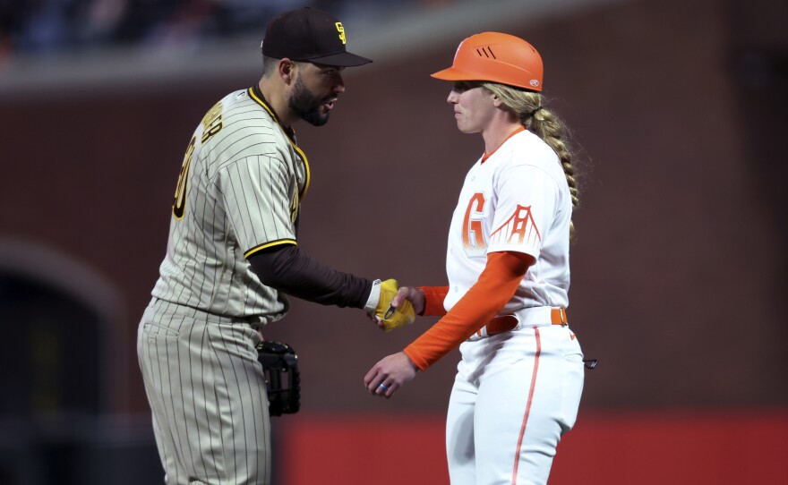 San Diego Padres first baseman Eric Hosmer, left, shakes hands with San Francisco Giants first base coach Alyssa Nakken on Tuesday.