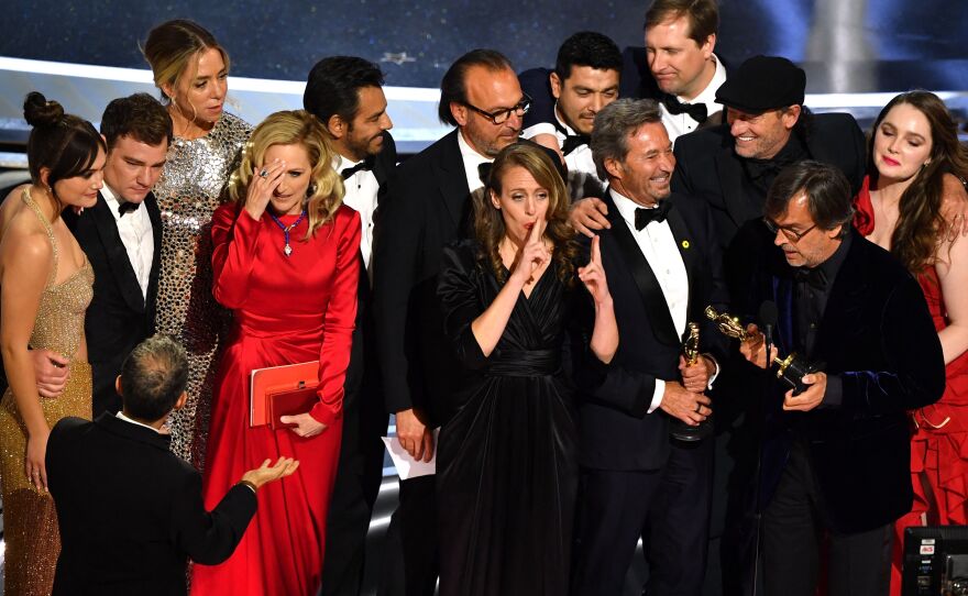 The cast and crew of CODA accept their award onstage.