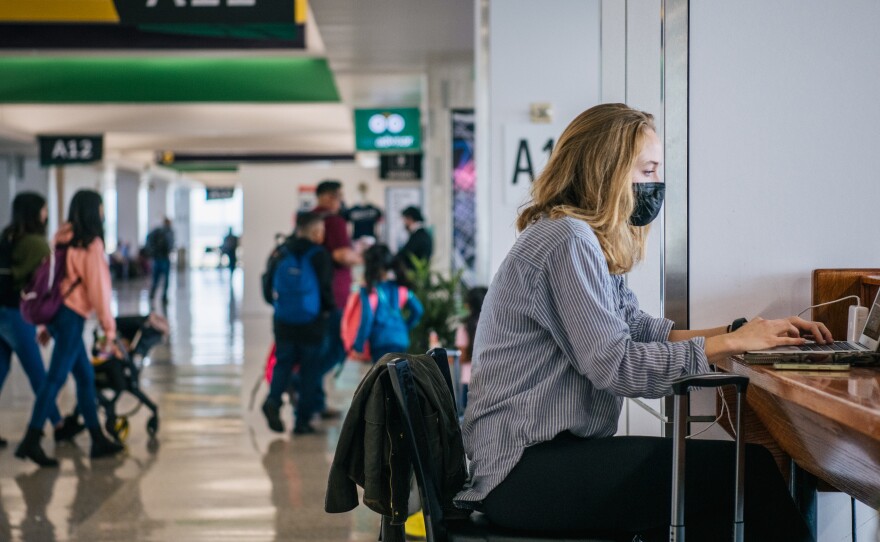 The CEOs of the major U.S. airlines have called on President Biden to end the federal mask mandate for public transportation. Here, a traveler works on a laptop computer at George Bush Intercontinental Airport in Houston on Dec. 3.