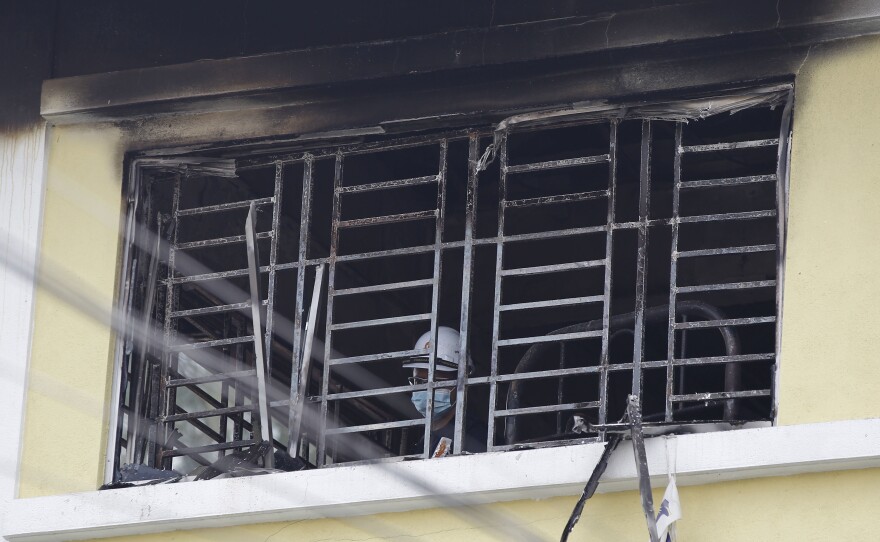 A forensic police officer investigates a dormitory window at a religious school in Malaysia after a fire that killed about two dozen people Thursday.