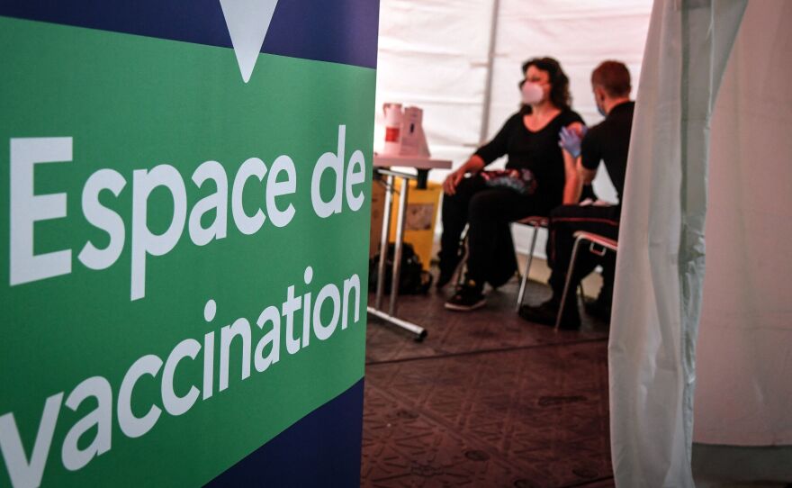 A firefighter administers the Pfizer-BioNTech COVID-19 vaccine at a vaccination center near Paris on Monday. The European Union has signed a deal to buy as many as 1.8 billion doses.