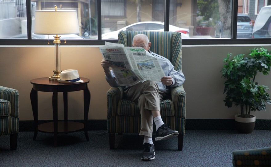 Walter Egger reads a newspaper in the common area at St. Paul's Manor in San Diego's Bankers Hill neighborhood, March 24, 2020.