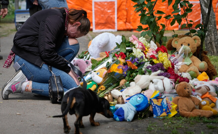A woman cries as she lays down flowers in front of a house heavily damaged after a Russian strike on residential neighbourhood in Kyiv, Ukraine, on Friday, May 15, 2026.
