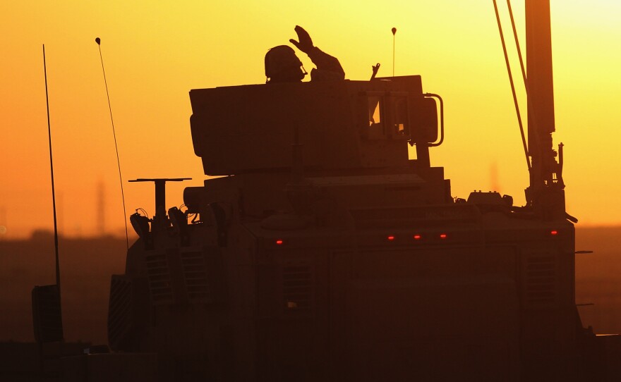 A soldier in the last American military convoy to depart Iraq, from the 3rd Brigade, 1st Cavalry Division, waves after crossing over the border into Kuwait on Dec. 18, 2011.