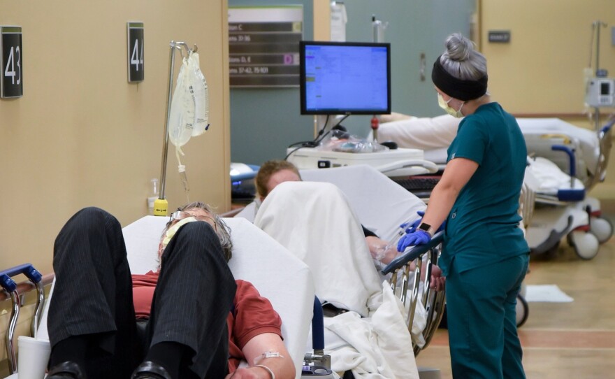 A nurse talks to a patient on a stretcher in the hallway of the Emergency Department at Sparrow Hospital.