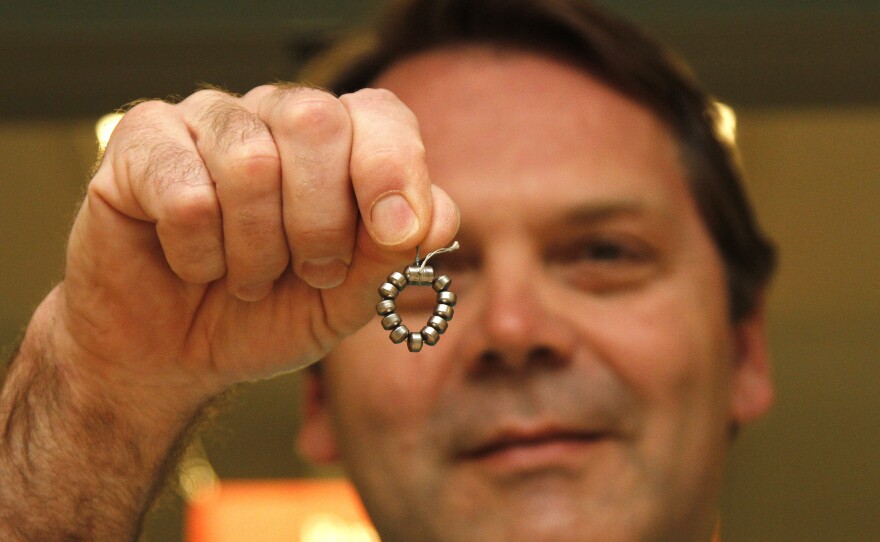 Dr. Ted Trus holds a magnetic ring of beads called a LINX. It has been approved by the Food and Drug Administration for people who aren't helped by medications.