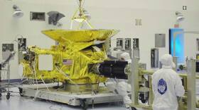Technicians at NASA Kennedy Space Center install the radioisotope thermoelectric generator (RTG) onto the New Horizons spacecraft.