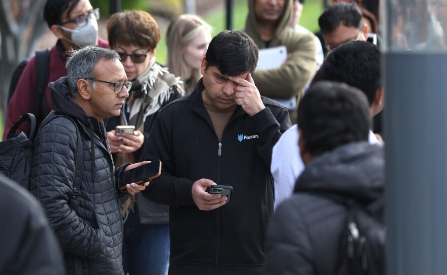 People line up outside of a Silicon Valley Bank office in Santa Clara, Calif., on March 13, 2023, the day after regulators swept in to protect depositors at the failed lender. Despite the emergency action, panicked depositors sought to withdraw money from smaller and regional lenders.