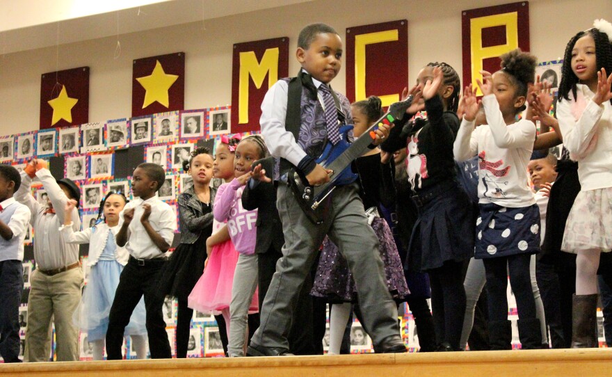 First grade students rock out to "Let's Go Crazy," honoring their chosen black icon, singer-songwriter Prince.