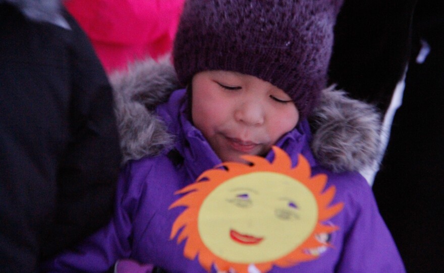 Julianne Kuko, 9, holds a drawing of the sun as she and her classmates perform a song to welcome the first sunrise in 58 days.
