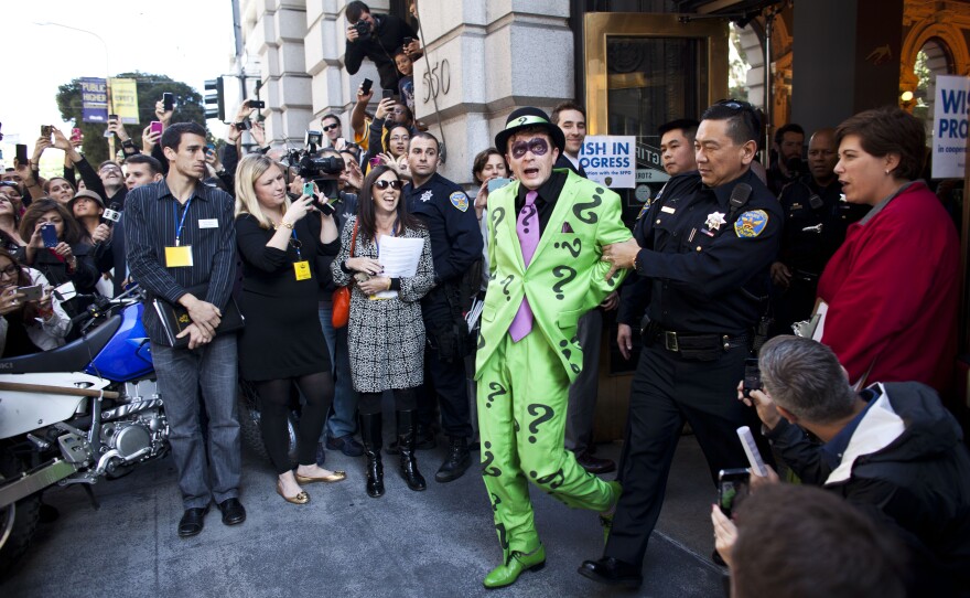 Police officers arrest The Riddler with the help of 5-year-old leukemia survivor Miles, also known as Batkid.