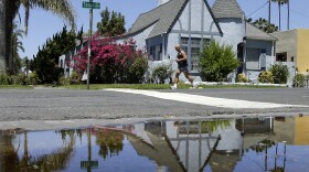 A house on Texas Street is reflected in a puddle of water from an irrigated front yard, July 9, 2014.