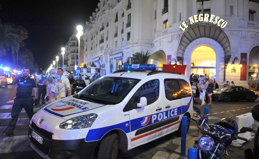 A police car is parked near the scene of an attack after a truck drove on to the sidewalk and plowed through a crowd of revelers who had gathered to watch the fireworks in Nice.