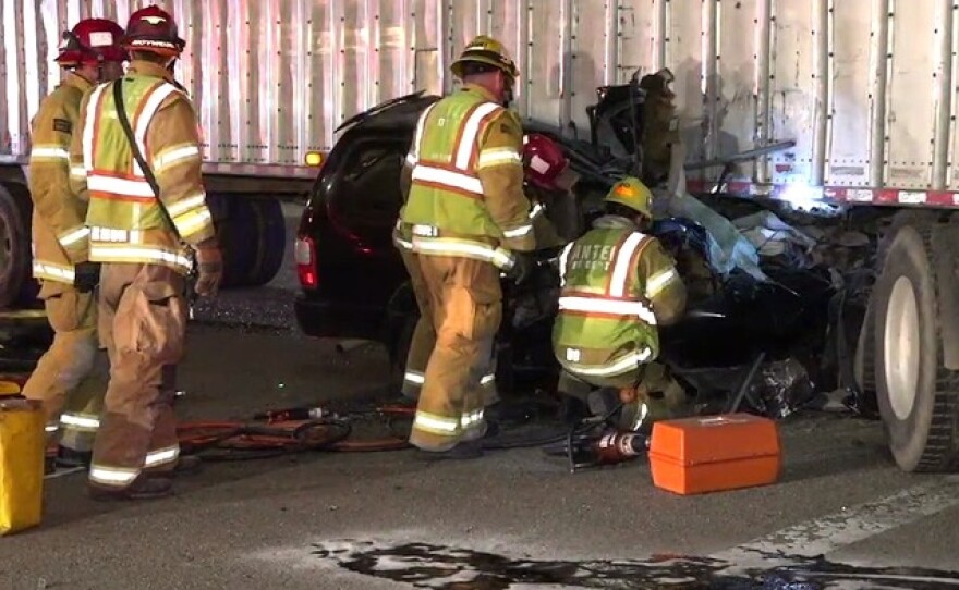 Santee firefighters attempt to rescue a person trapped in a car that crashed into a semi-truck on State Route 52 in Santee, April 13, 2016.