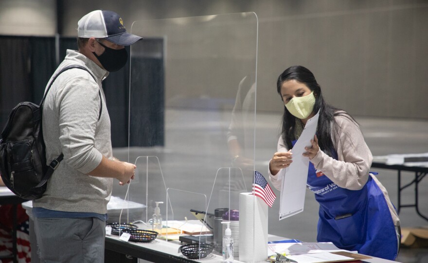 Election worker Lizana Guzman gives a voter his ballot at the San Diego Convention Center polling location, Nov. 2, 2020.