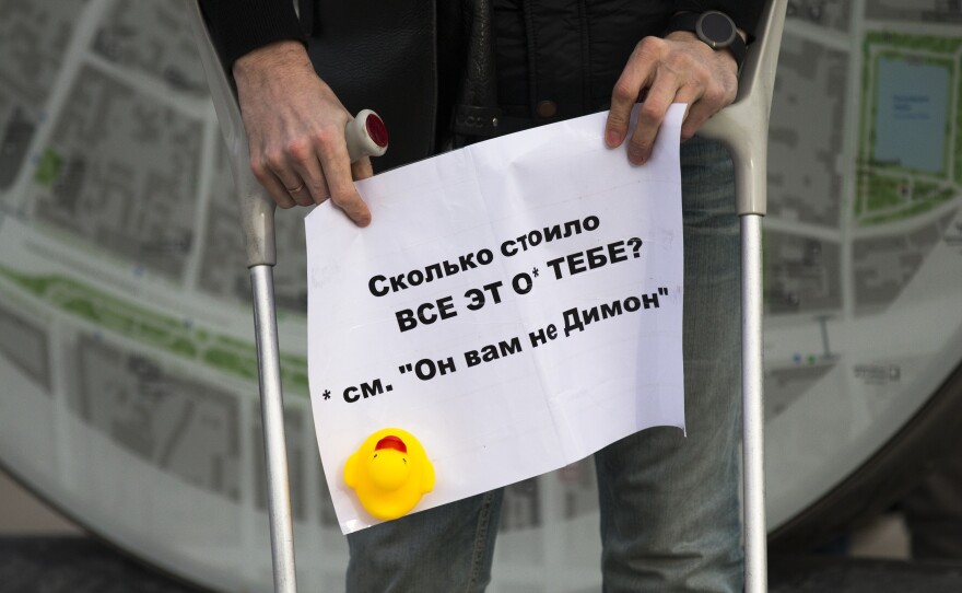 A man holds a poster saying "How Much Did it Cost You?" with a yellow duck toy in downtown Moscow on Sunday. The protests focused on reports claiming that Prime Minister Dmitry Medvedev has amassed a collection of mansions, yachts and vineyards — and a house for raising ducks.