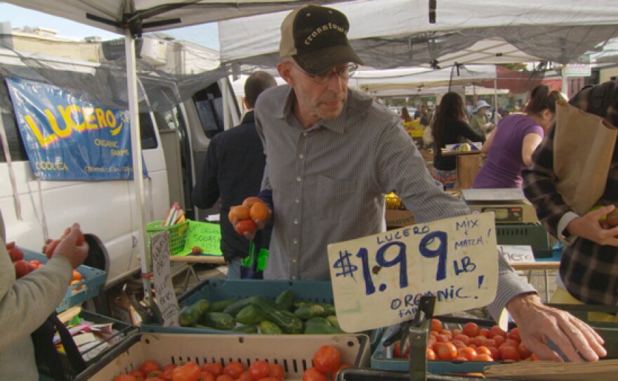 Michael Pollan shops for vegetables at a farmers market.