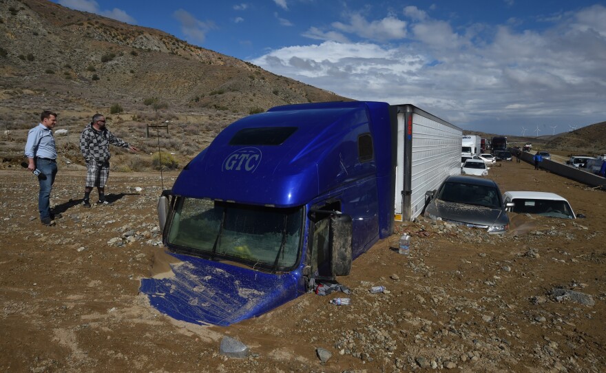 Reporters look vehicles stuck on a road after being trapped by a mudslide on California Highway 58 in Mojave on Saturday.