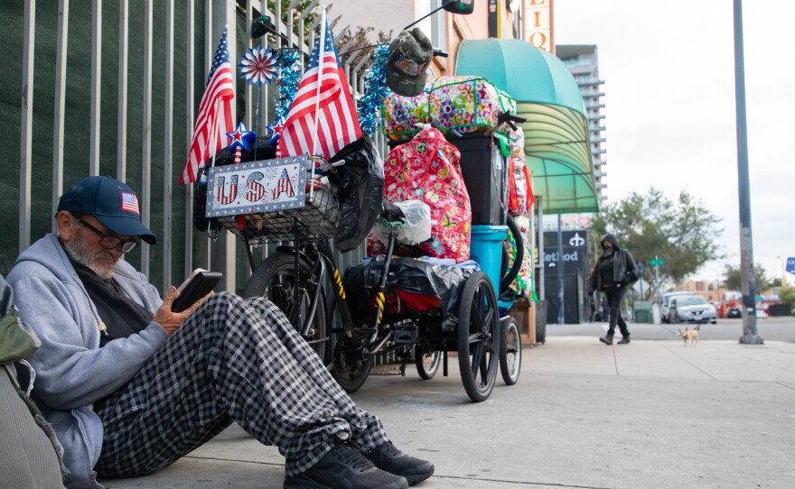 Eddie Richardson, who says he’s a Vietnam War veteran, looks at his phone while sitting next to his bike on 16th Street in San Diego, May 20, 2020.
