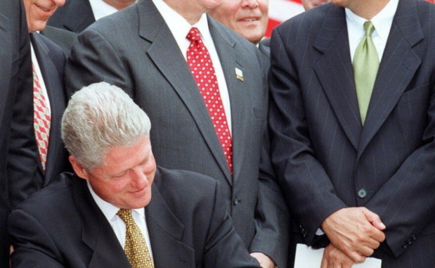 House Speaker Newt Gingrich talks with Rep. John Kasich of Ohio while President Bill Clinton signs the Balanced Budget Agreement on the South Lawn of the White House in 1997.
