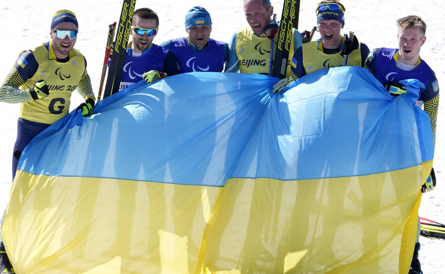 Guide Oleksandr Mukshyn, Anatolii Kovalevskyi, Vitalii Lukianenko, guide Borys Babar, guide Oleksandr Nikonovych and Dmytro Suiarko celebrate their sweep in the men's middle distance vision impaired para biathlon at the 2022 Winter Paralympics on Tuesday in China.