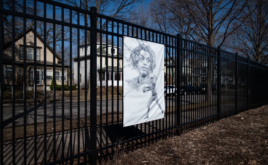 A portrait of Deshaun Hill Jr. hangs outside on the fence surrounding the North Community High School track and football field in Minneapolis.