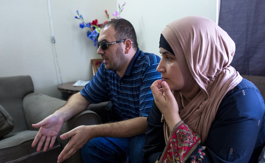 Mostafa Inezan, (left) and his wife, Waelah, speak with a family friend (not pictured) while sitting on a couch in the family's new three-bedroom apartment, July 25, 2017.