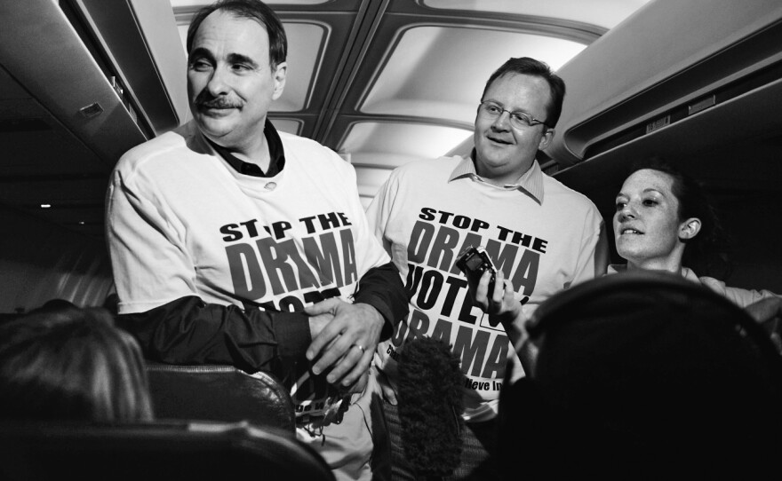 Chief campaign strategist David Axelrod (left) and communications director Robert Gibbs talk to members of the traveling press corps during a flight leading up to the Pennsylvania primary in 2008.