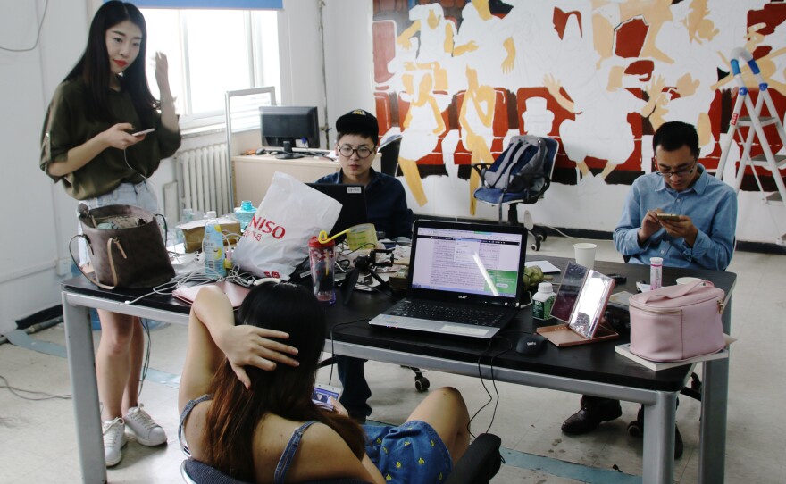 Huang Xian'er (left) looks at her smartphone at the Beijing-based Internet talent company where she works.