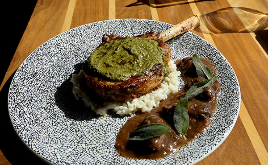 Pan-Seared Veal Chop: A 14 oz veal chop served with garden herb gremolata, risotto, and morel mushroom jus.