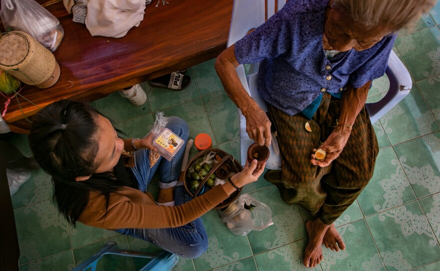 A passes <em>paan — </em>a stimulant chew made of betel leaves and other ingredients — to her grandmother. Since moving back to her home village, A spends most of her time taking care of her.