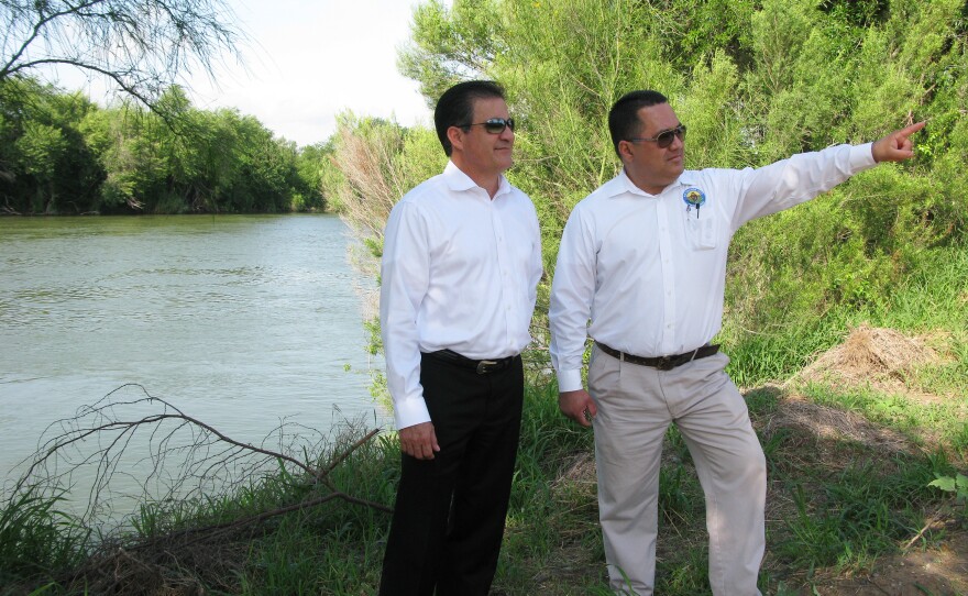 Alberto Perez, Rio Grande City manager (left), and Gilbert Millan, the city's planning director, walk along the riverbank to show how close the earlier planned fence would be located next to the water.