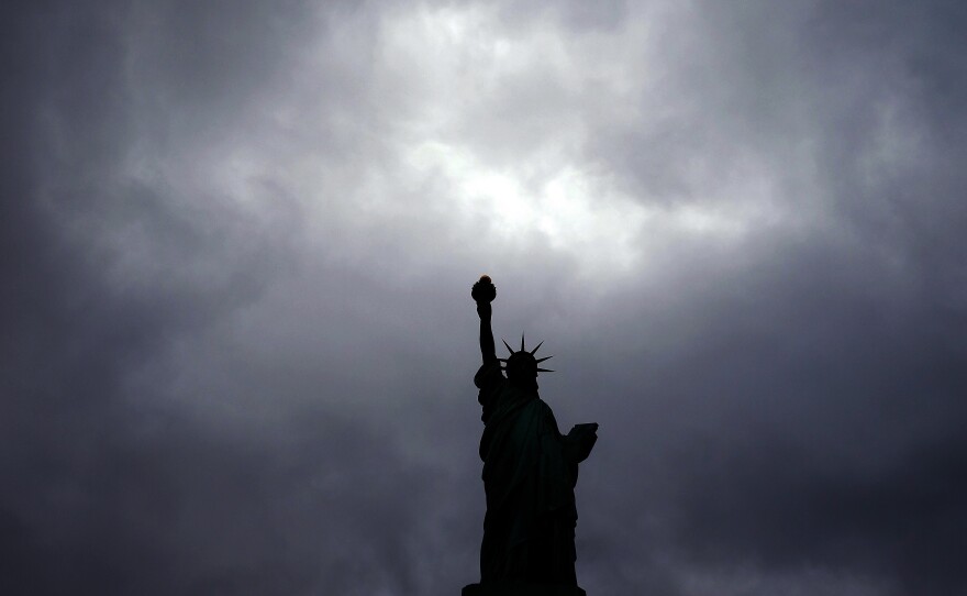 The Statue of Liberty stands tall as dark clouds cover the New York sky.