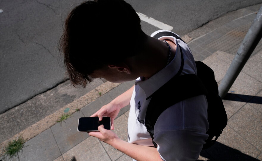 FILE - A teenage boy uses his phone in Sydney, Nov. 8, 2024.