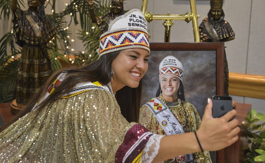 Outgoing Jr. Miss Florida Seminole Cheyenne Nunez snaps a selfie with her portrait at the Miss Florida Seminole pageant on July, 25, 2015 in Hollywood, Fla. Every Miss Florida Seminole from 2005 to the present has been memorialized in the bronze statues behind her.