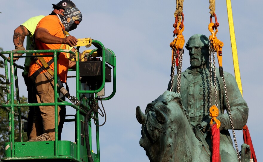 Workers remove a statue of Confederate Gen. Robert E. Lee from Market Street Park on Saturday in Charlottesville, Va.